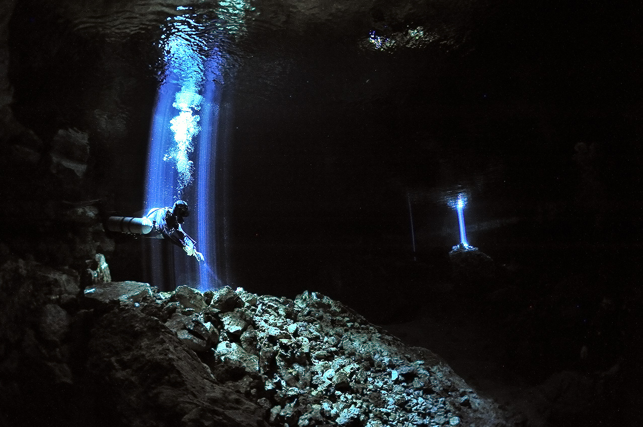 Un plongeur dans un rayon de lumière qui passe à travers un trou dans la voûte du cénote - Mexique