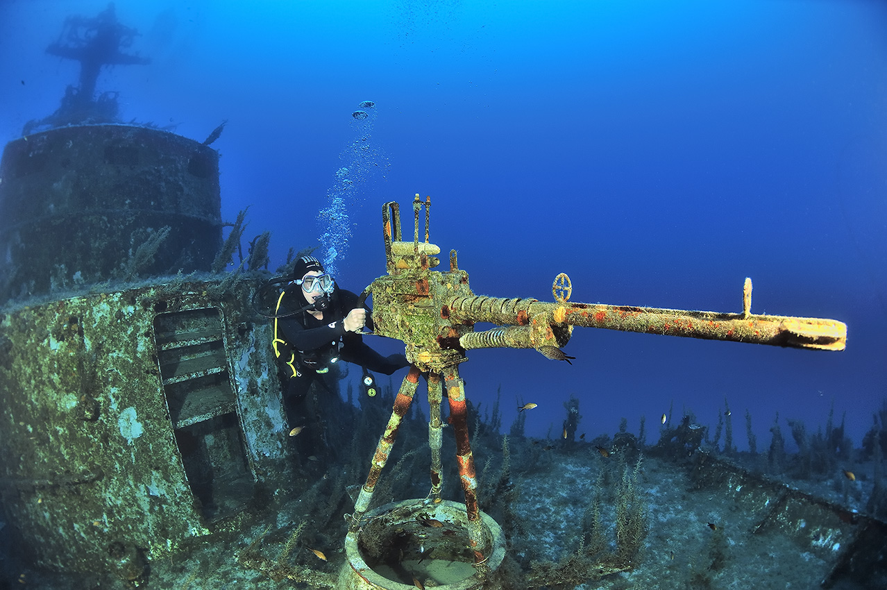 Un plongeur à côté de la mitrailleuse sur le pont d’un patrouilleur coulé comme récif artificiel – Malte